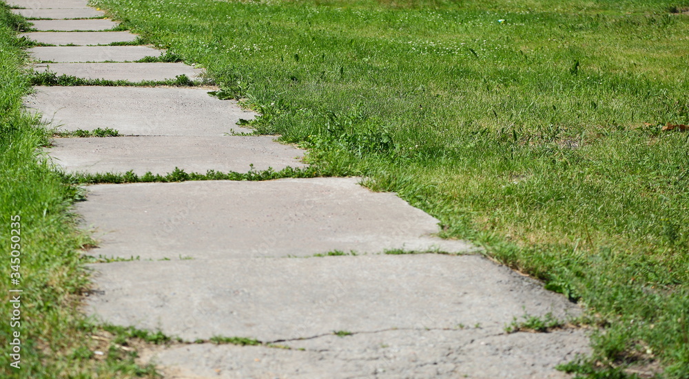 Gray concrete pathway without fence in green grass Gray concrete pathway without fence in green grass