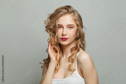 Perfect woman with long blonde curly hair on white background