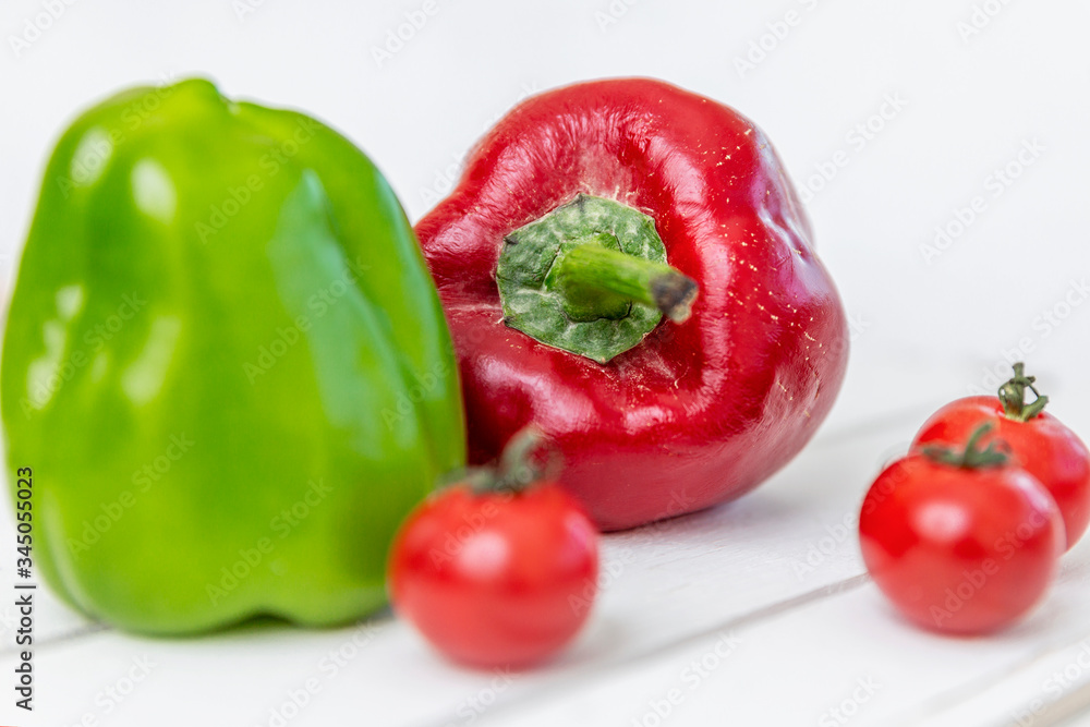 Sweet red and green peppers and cherry tomatoes on a white wooden table. Vitamins and a healthy lifestyle. Sweet red and green peppers and cherry tomatoes on a white wooden table. Vitamins and a healthy lifestyle.