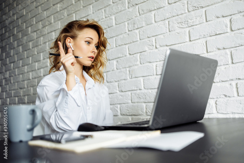Woman with curly hair sitting at table with laptop.