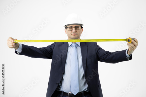 Handsome construction engineer in hard hat holding measuring tape seriously looks at camera isolated on white background. Successful man from industrial sphere, architectural project concept photo