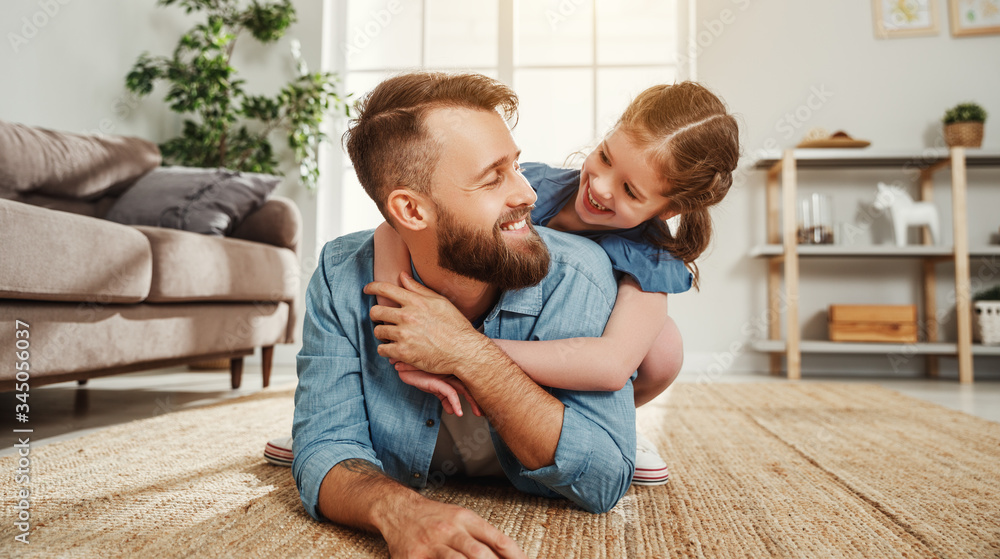 Cheerful father and daughter having fun and hugging in living room. Cheerful father and daughter having fun and hugging in living room.