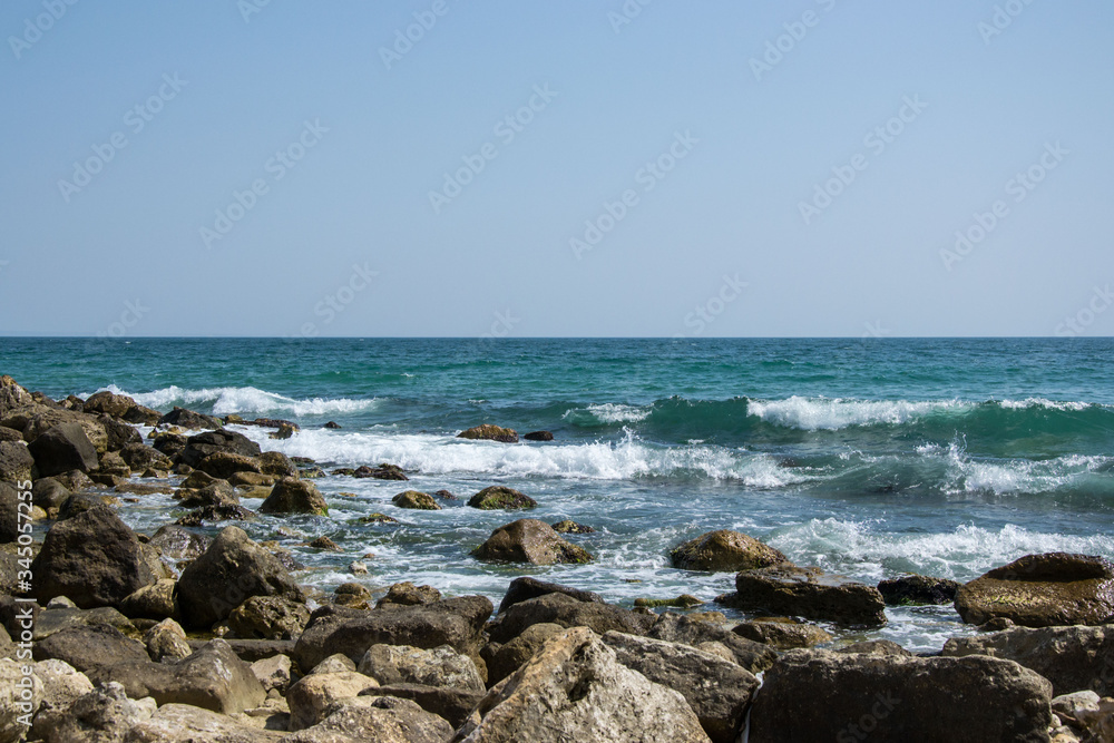 Beautiful wild beach landscape, sunny day, water waves hitting the cliffs, nature summertime scene