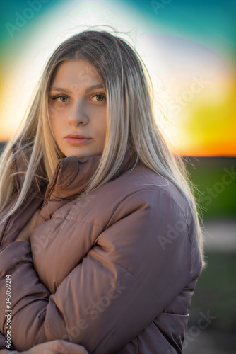 Portrait of a blonde in a gray jacket at sunset. Photographed close-up.