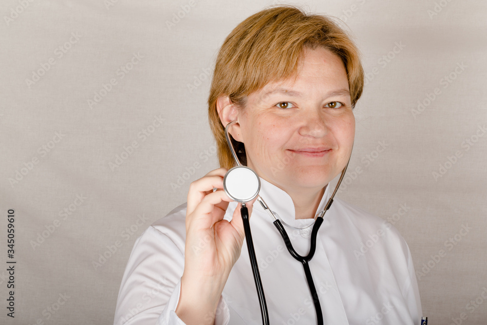 Female doctor with phonendoscope on her neck smiles for you