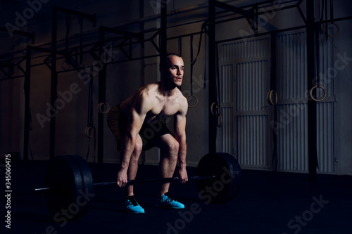Athletic man doing barbell workout at gym. Deadlift exercise example.