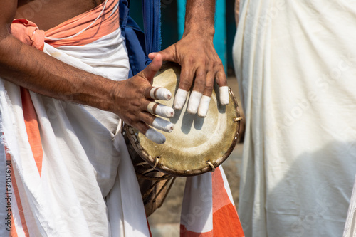 A person playing an instrument called Timila which is made of polished jackwood and held together by leather brazes. It is one of the five musical instrument in Panchavadyam . photo