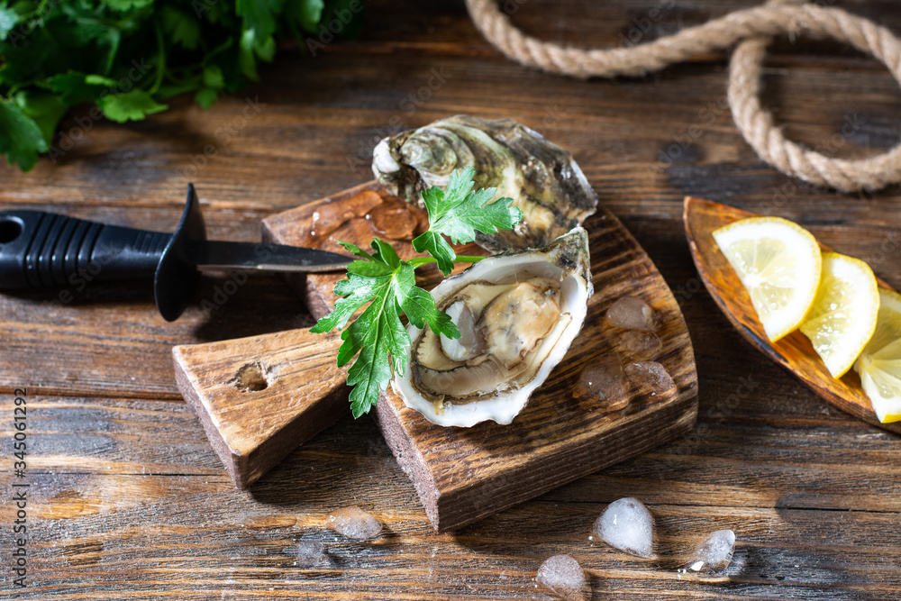 Fototapeta premium Two oysters on a wooden Board against the background of a basket of oysters 