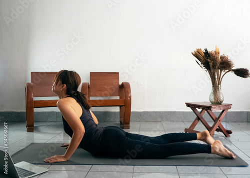 Woman wearing exercise suit,bend back body up,strteching body on yoga mat,at home photo