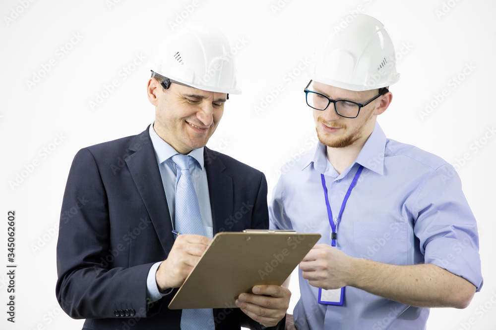 Smiling engineer and architect in hard hats discuss finished successful project while making notes in clipboard, making calculated engineering decisions isolated on white background. BIM construction