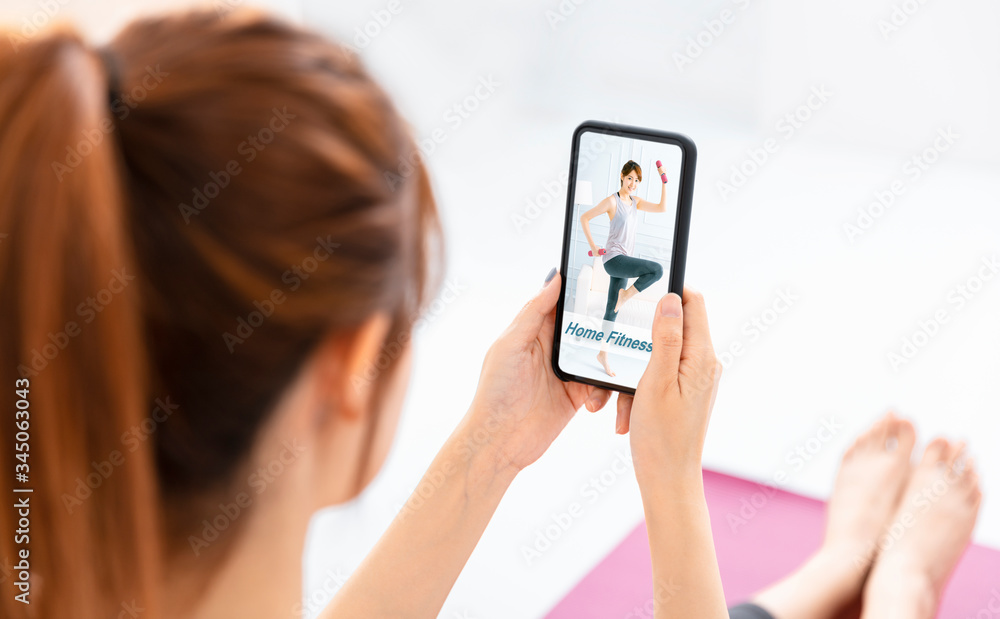Young woman watching mobile phone training lesson app doing exercises at home Young woman watching mobile phone training lesson app doing exercises at home
