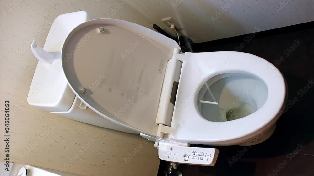 Water sprays from toilet bowl, first version of stream. Toilet bowl with electronic control bidet. A cleansing jet of water designed to cleanse the anus of the user of this bidet-style toilet. Water sprays from toilet bowl, first version of stream. Toilet bowl with electronic control bidet. A cleansing jet of water designed to cleanse the anus of the user of this bidet-style toilet.