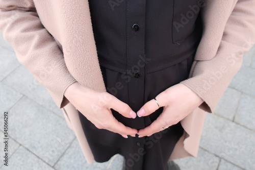 
girl's hands connecting heart shape on belly
