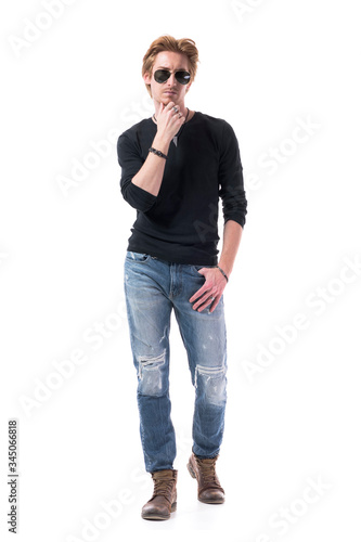 Confident thoughtful handsome young redhead man walking towards camera with hand on chin. Full body isolated on white background. 