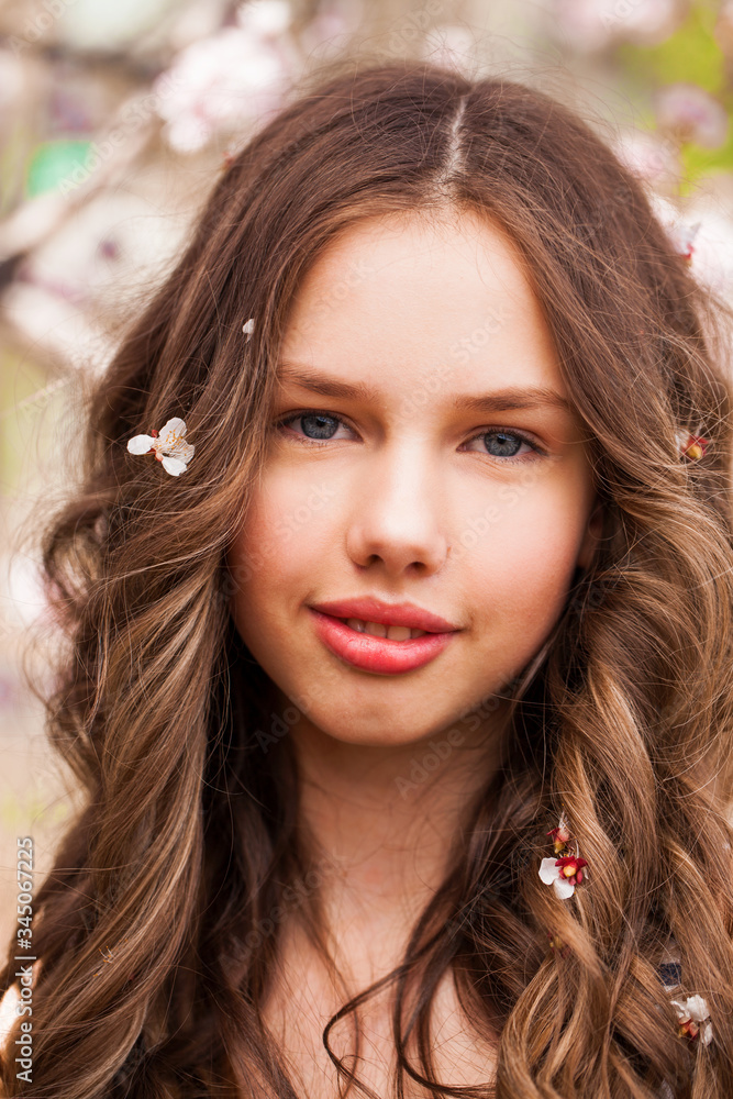 Young girl posing near blossom cherry tree with pink flowers Young girl posing near blossom cherry tree with pink flowers
