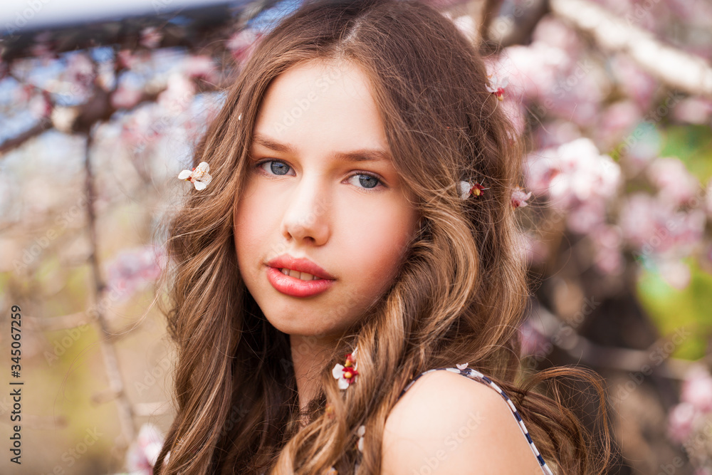 Young girl posing near blossom cherry tree with pink flowers Young girl posing near blossom cherry tree with pink flowers