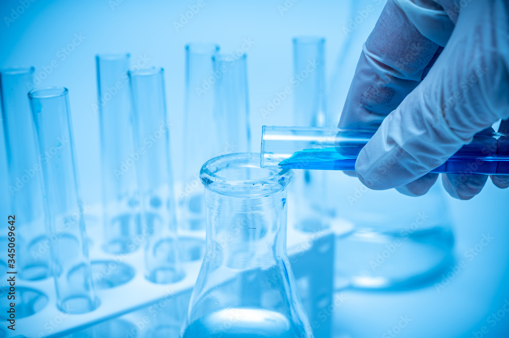 A researcher's hand holding a test tube containing blue liquid. A researcher's hand holding a test tube containing blue liquid.