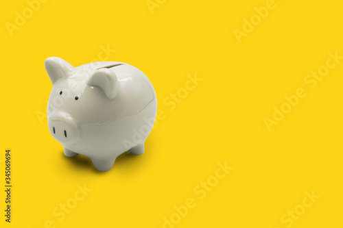 white piggy bank isolated on yellow background ,with copy space