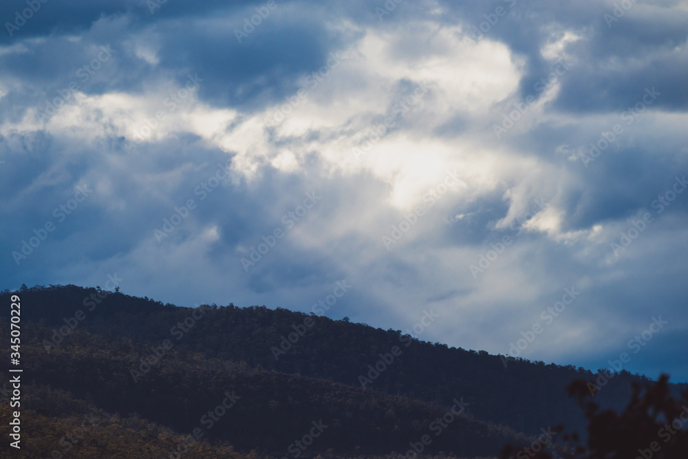Australian mountain landscape with clouds and intense sunrays, shot in Tasmania over Mount Wellington