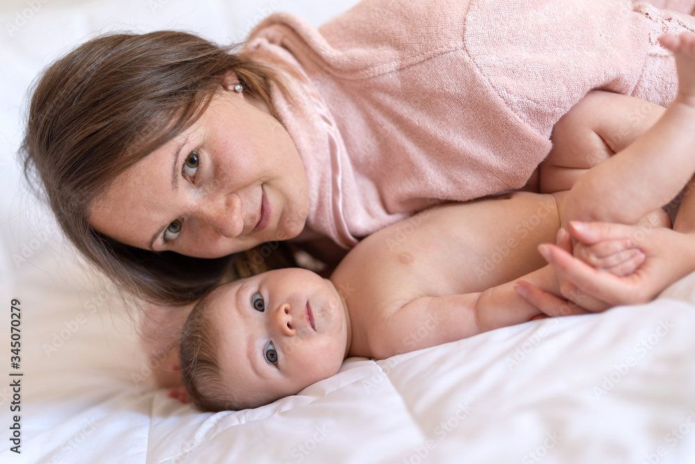 Mother and baby girl relaxing at home lying in bed together Mother and baby girl relaxing at home lying in bed together