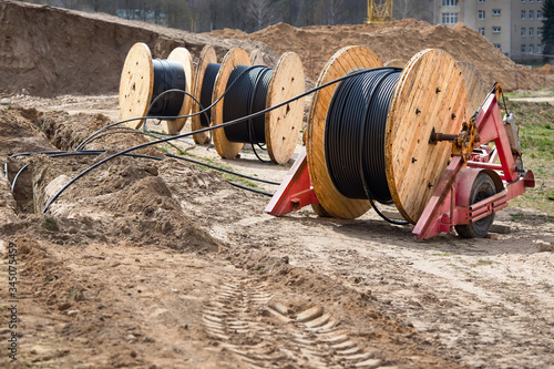Several wooden coils with power cable laid in trench. Concept of electricity supply for construction projects.