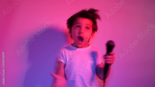 fashionable boy in a white t shirt sings into a karaoke microphone at home
