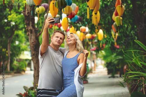 Fotografie Couple a man and a woman take a selfie on a smartphone together on the street of