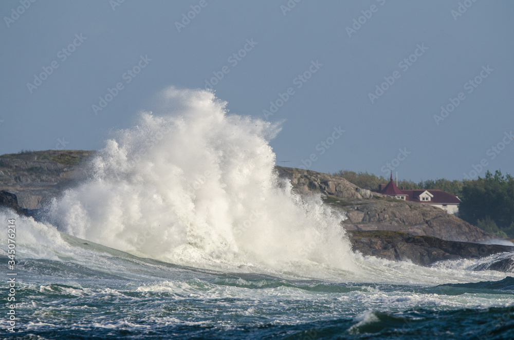 Obraz premium High waves hit cliffs, windy day by the sea on Sweden's west coast, Öckerö, the northern archipelago of Gothenburg. Blue sky background with copy space and place for text.