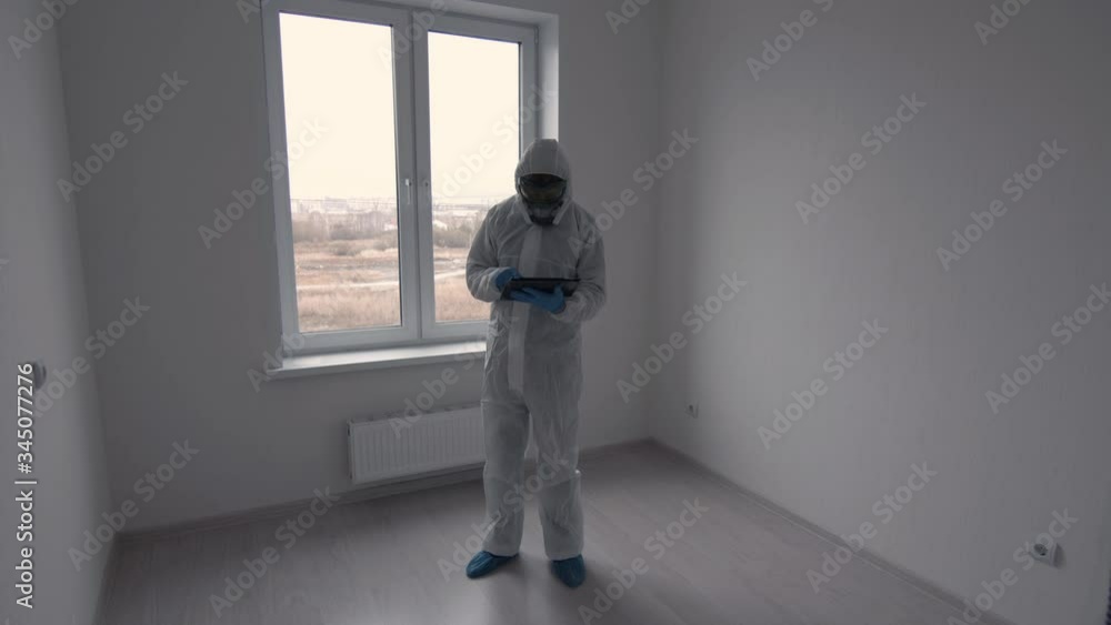 Man in bio-protective suit works in a white room Man in bio-protective suit works in a white room