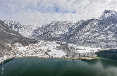 Aerial drone shot of Obertraun village in snow mountain valley by Hallstatt lake in Austria in winter