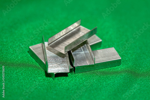 Metal staples on green background