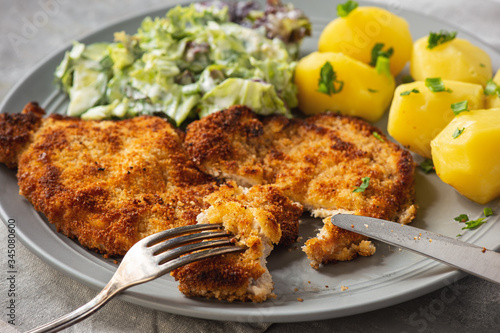 Chop pork cutlets , served with boiled potatoes and salad. photo