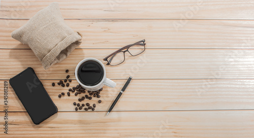 Wooden office desk with coffee cups and glasses on the side with a telephone, top view, Morning life at work concept.