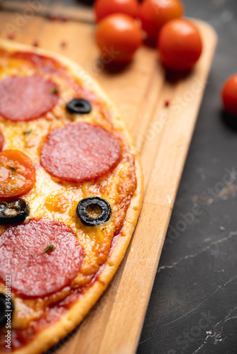Fresh pepperoni pizza served on the rustic background. Selective focus. Shallow depth of field.