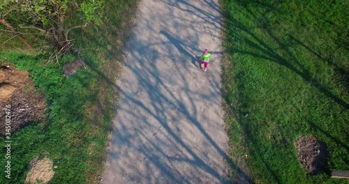 Little kid ride a scooter in a village on a spring day, video from a drone