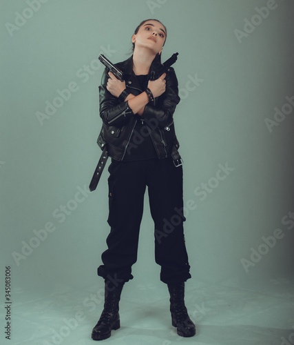 Shot of a sexy military woman posing with guns,in a black jacket