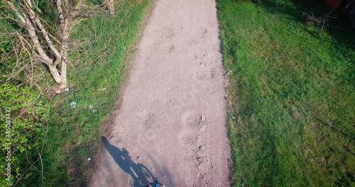 a little boy rides his bike in a rural location and videos with the drone