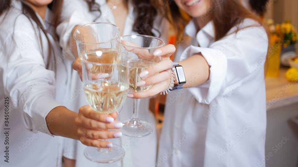 There's toast. A group of female friends in white shirts clink glasses with champagne. There's toast. A group of female friends in white shirts clink glasses with champagne.