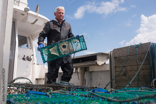 Man lowering lobster cage into the water