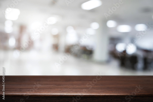 Empty wooden table and blurry background of white bokeh light department store for product display montage.