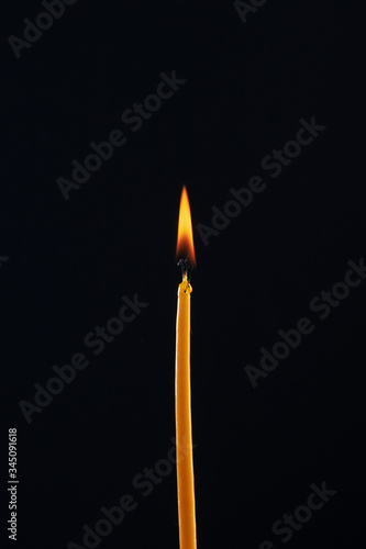 Burning church candle on a dark/black background.