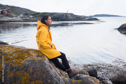 portrait of beautiful woman in yellow rain jacket in archipelago