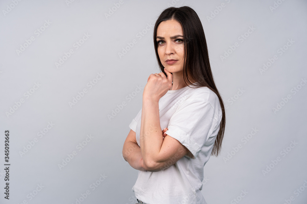 Young beautiful girl on a white background, stands with folded arms and strictly looks directly at the camera, expression of emotions Young beautiful girl on a white background, stands with folded arms and strictly looks directly at the camera, expression of emotions