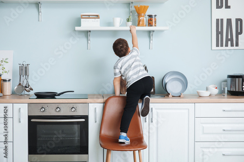 Little boy trying to reach out for pasta at home photo