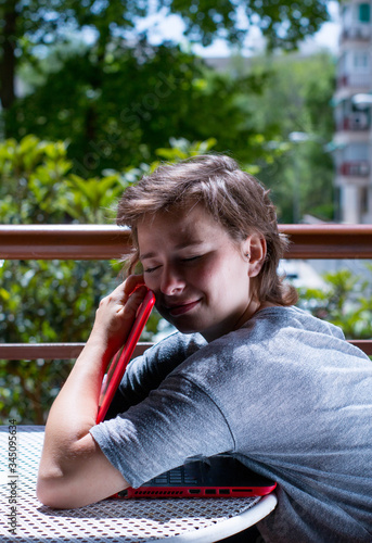 Young girl interacting with her laptop at her balcony on a sunny day at home. © J.F. Corado