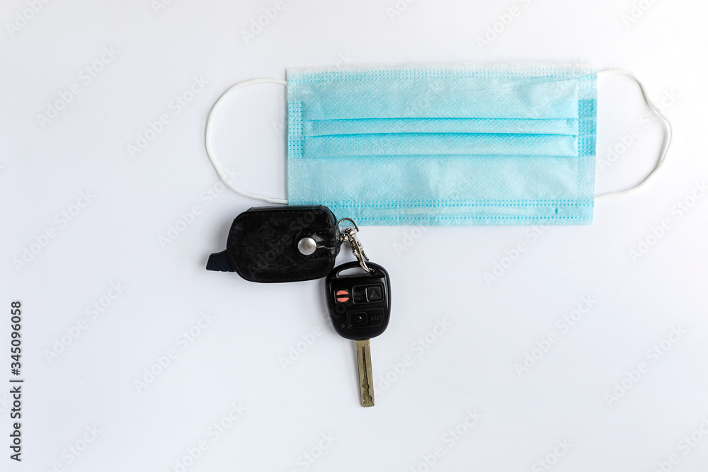 Car keys and medical mask on a white isolated background. Concept of the end of quarantine due to the coronavirus pandemic. Flat lay. Car keys and medical mask on a white isolated background. Concept of the end of quarantine due to the coronavirus pandemic. Flat lay.