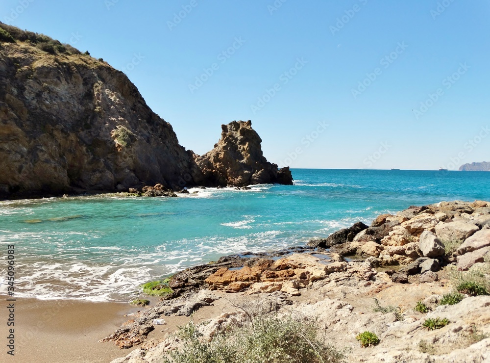 Panorama casi lunar con paisaje de playa de arena rojiza y paraje desértico con acantilados en la costa del Mar Mediterráneo dentro del Parque Regional de Calblanque en Murcia