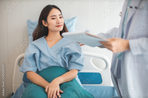  Medicine and health care concept.  Asian doctor is taking care patient woman in hospital.doctor or nurse wear protection mask checking and takecare infection people from covid-19 .