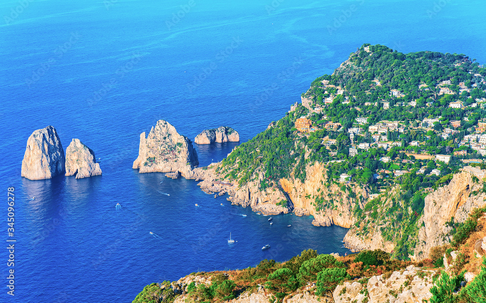 Boats near Faraglioni cliffs with Tyrrhenian Sea of Capri Island reflex
