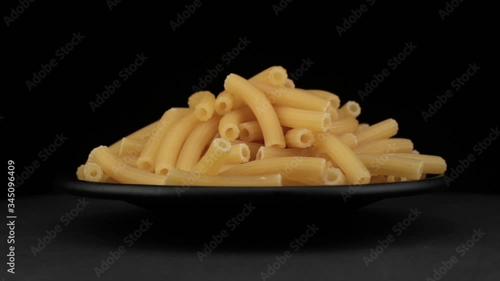 Pasta grains of spin around themselves on a black background and ground